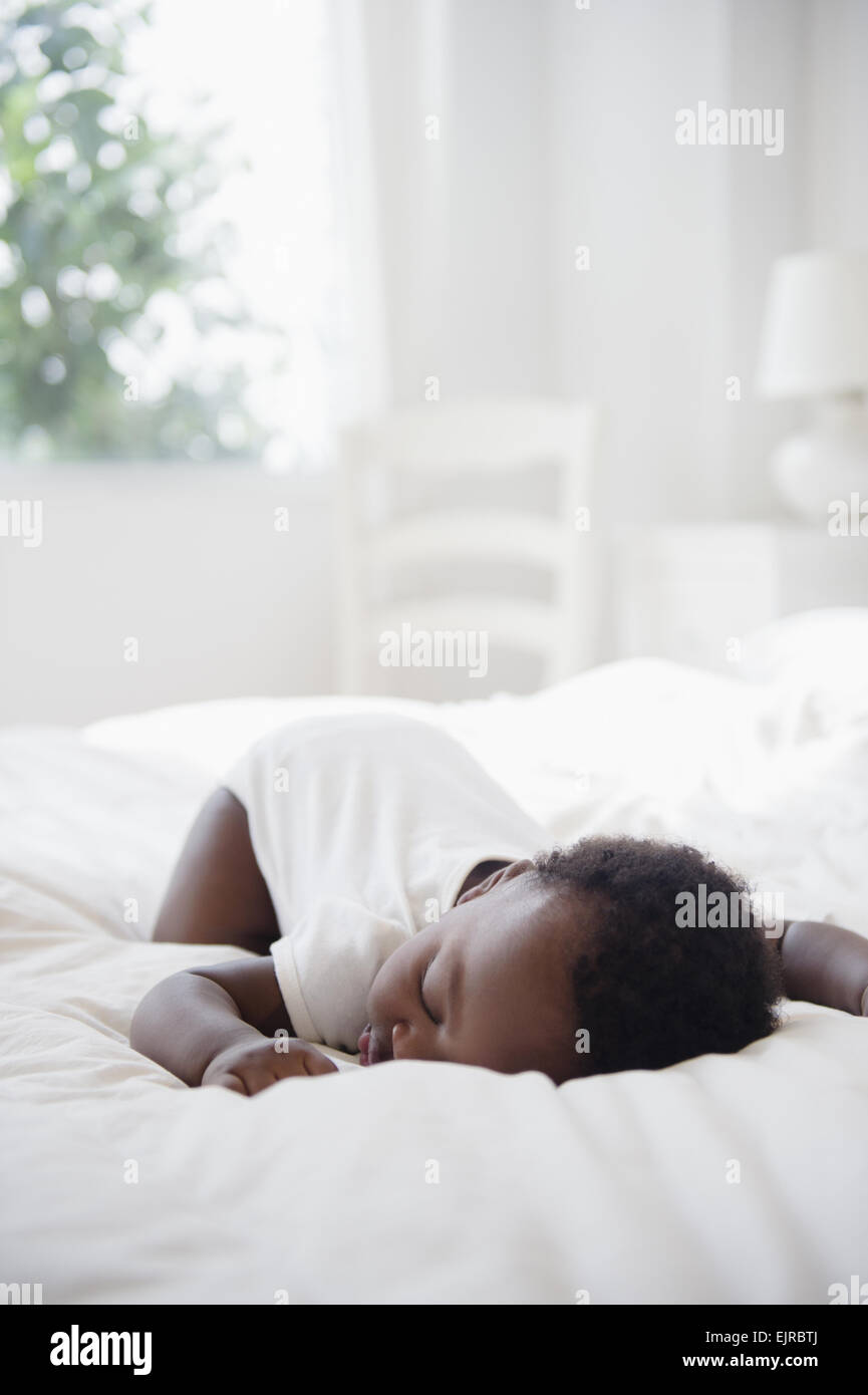 Black baby sleeping on bed Stock Photo