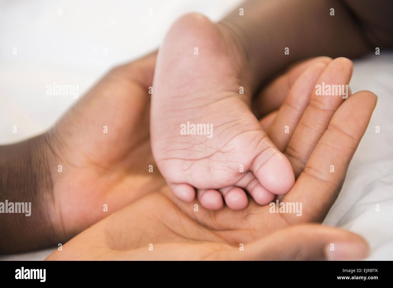 Close up of Black mother holding foot of baby Stock Photo