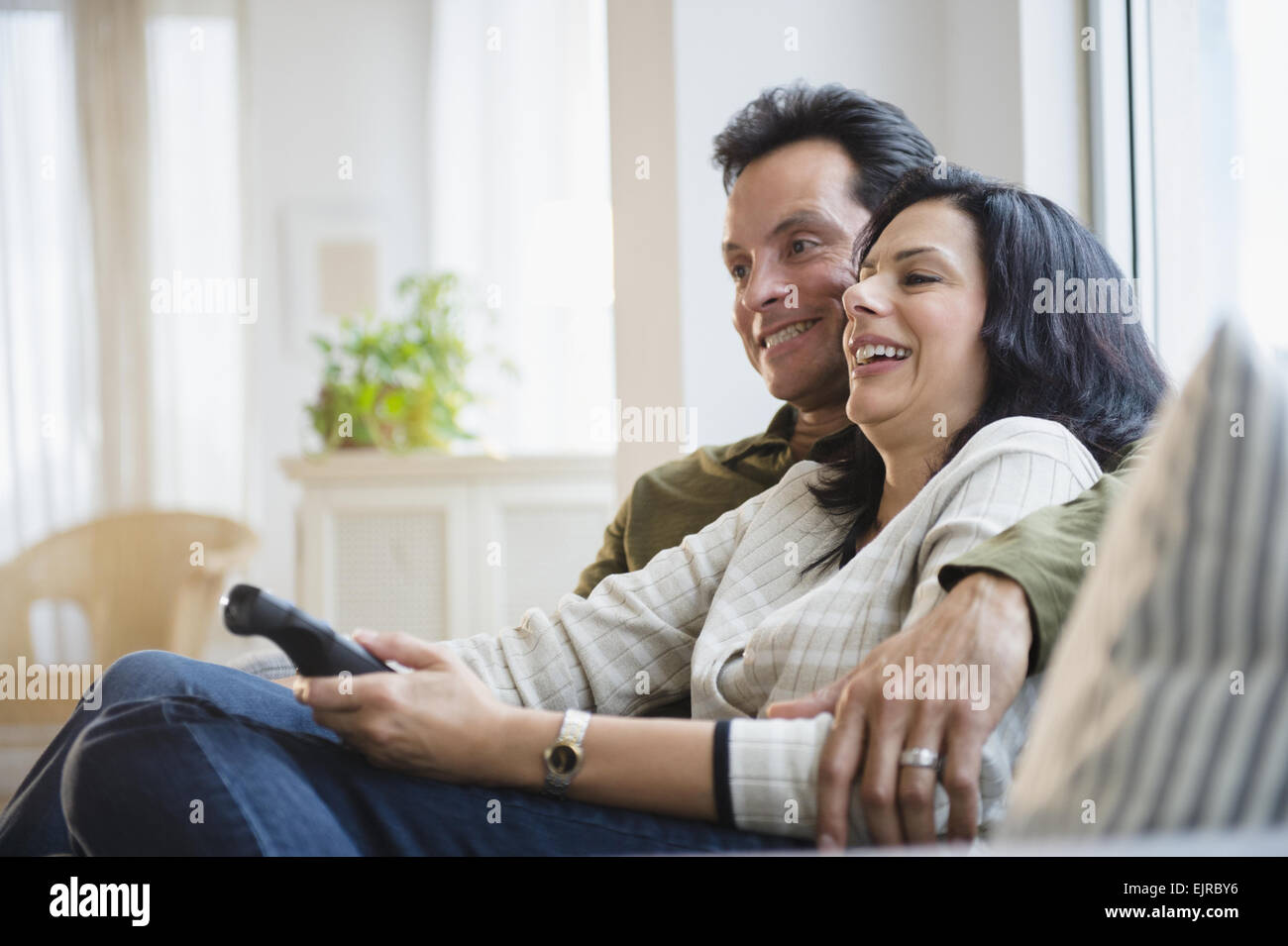 Couple watching television on sofa in living room Stock Photo