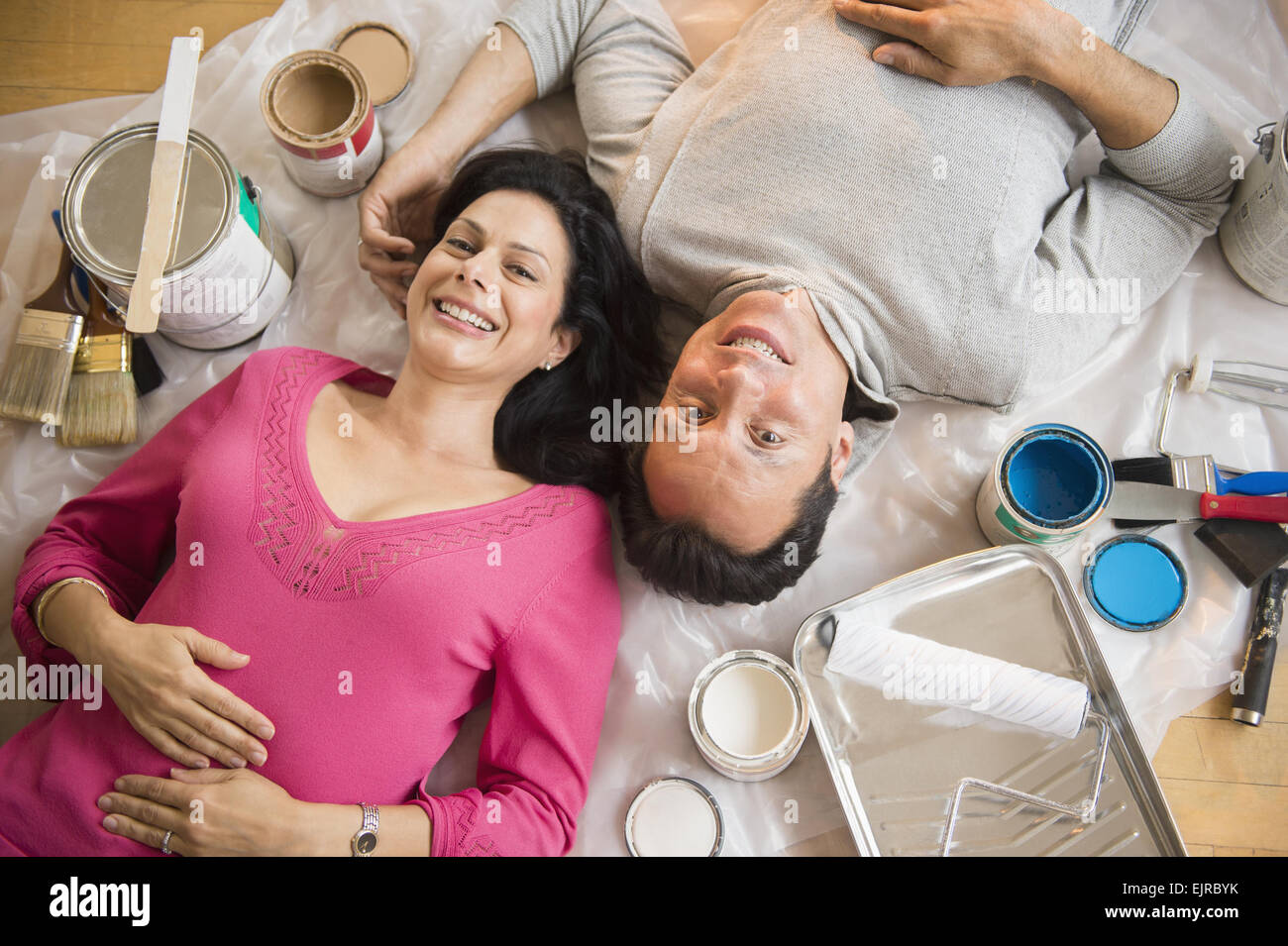 Overhead view of couple laying on drop cloth during remodeling Stock Photo