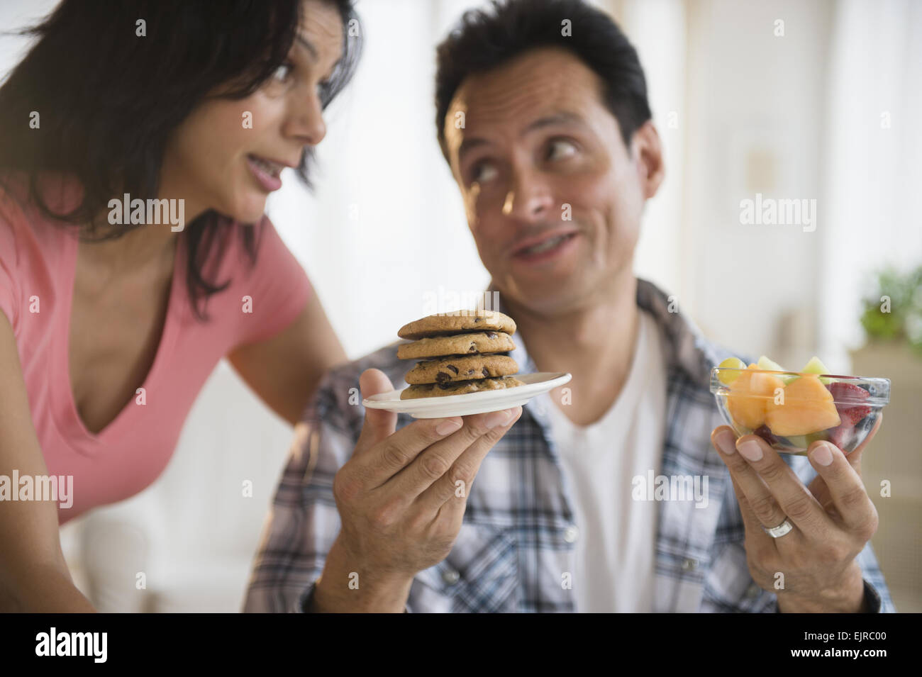 Couple choosing between healthy and unhealthy snacks Stock Photo