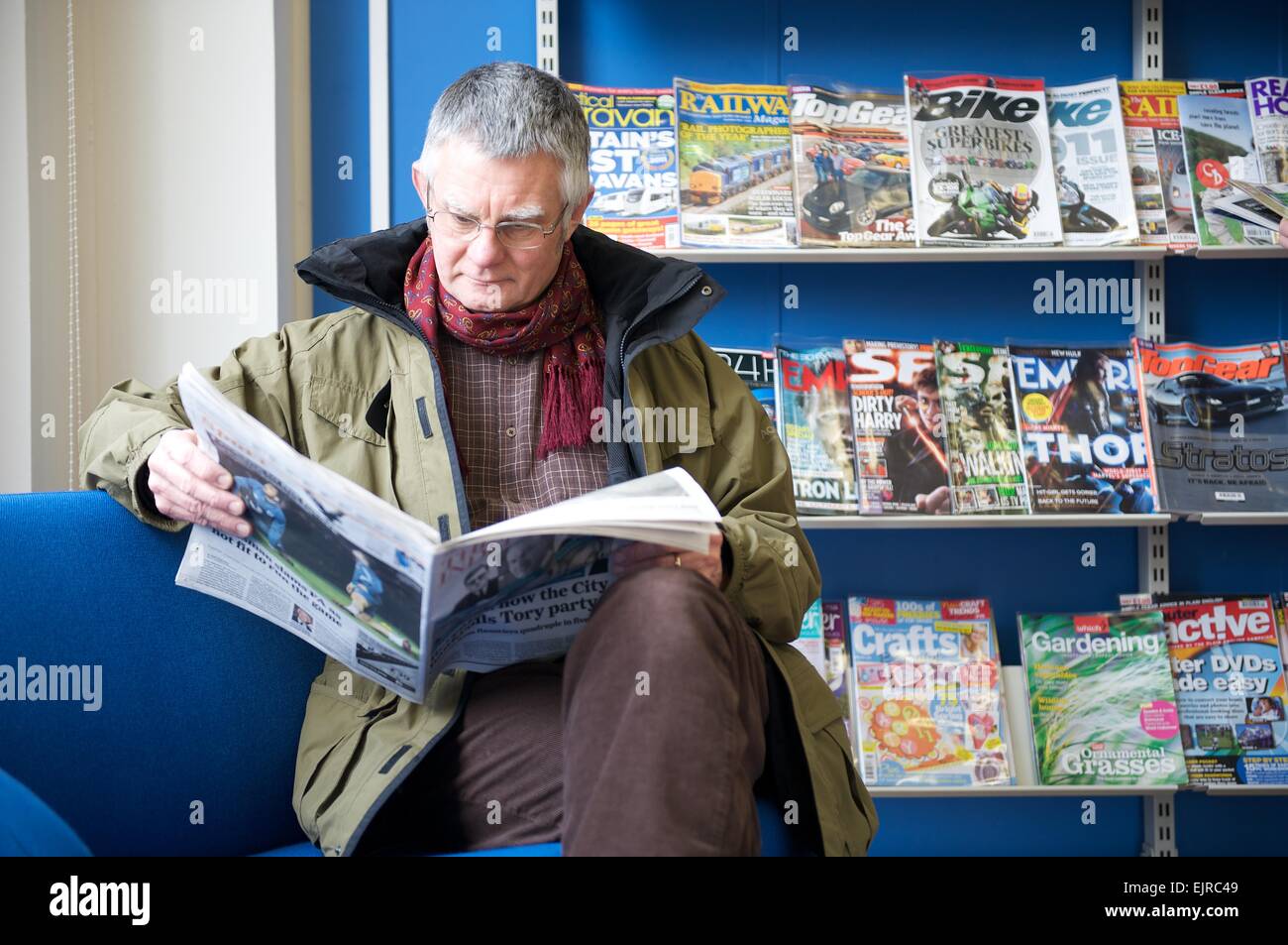 Senior man reading a newspaper in a public library Stock Photo