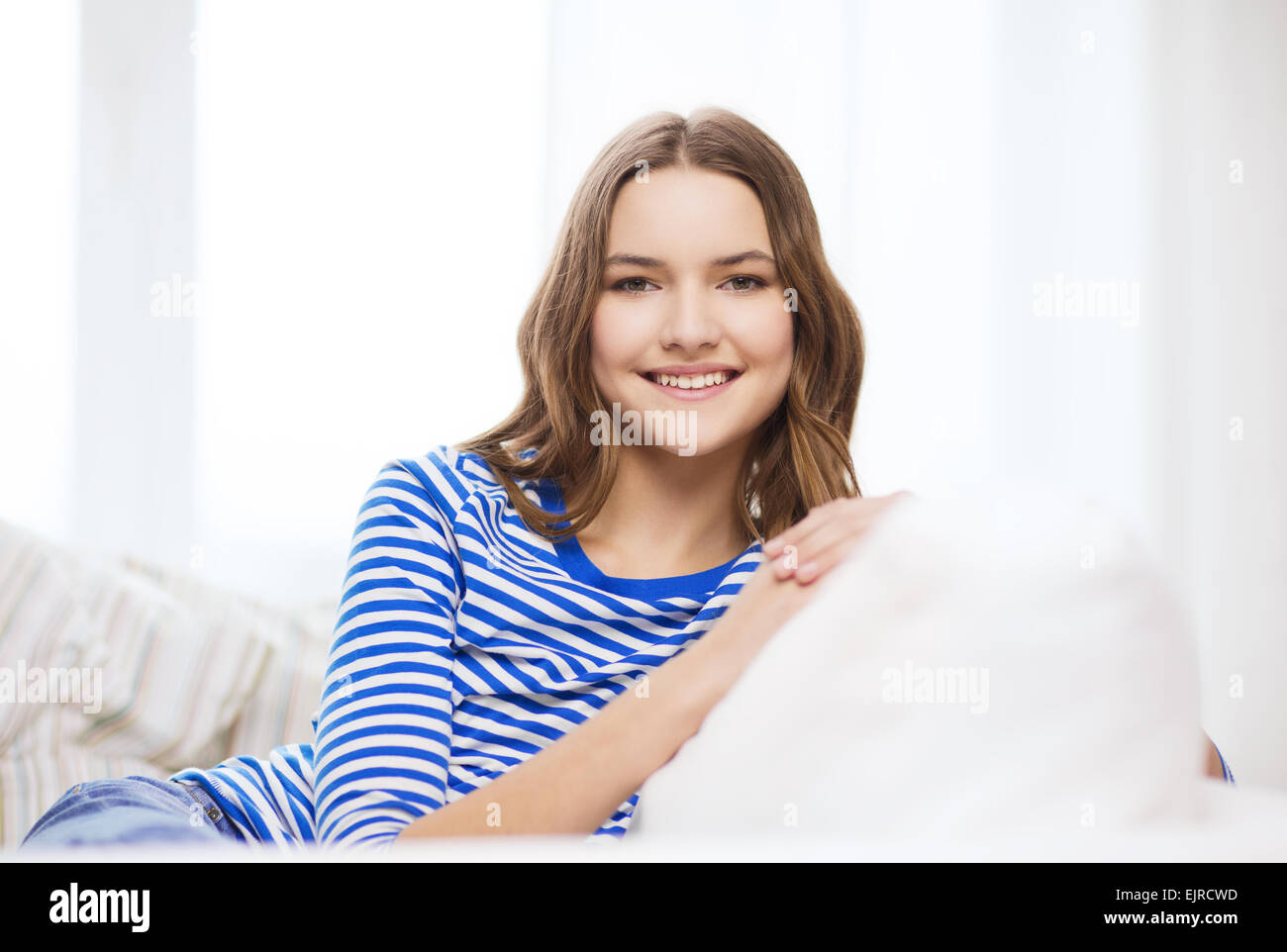 smiling teenage girl sitting on sofa at home Stock Photo - Alamy