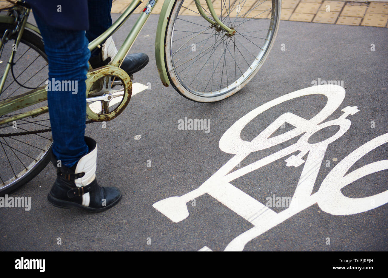 Cyclist stopped at junction with cycling symbol on road Stock Photo