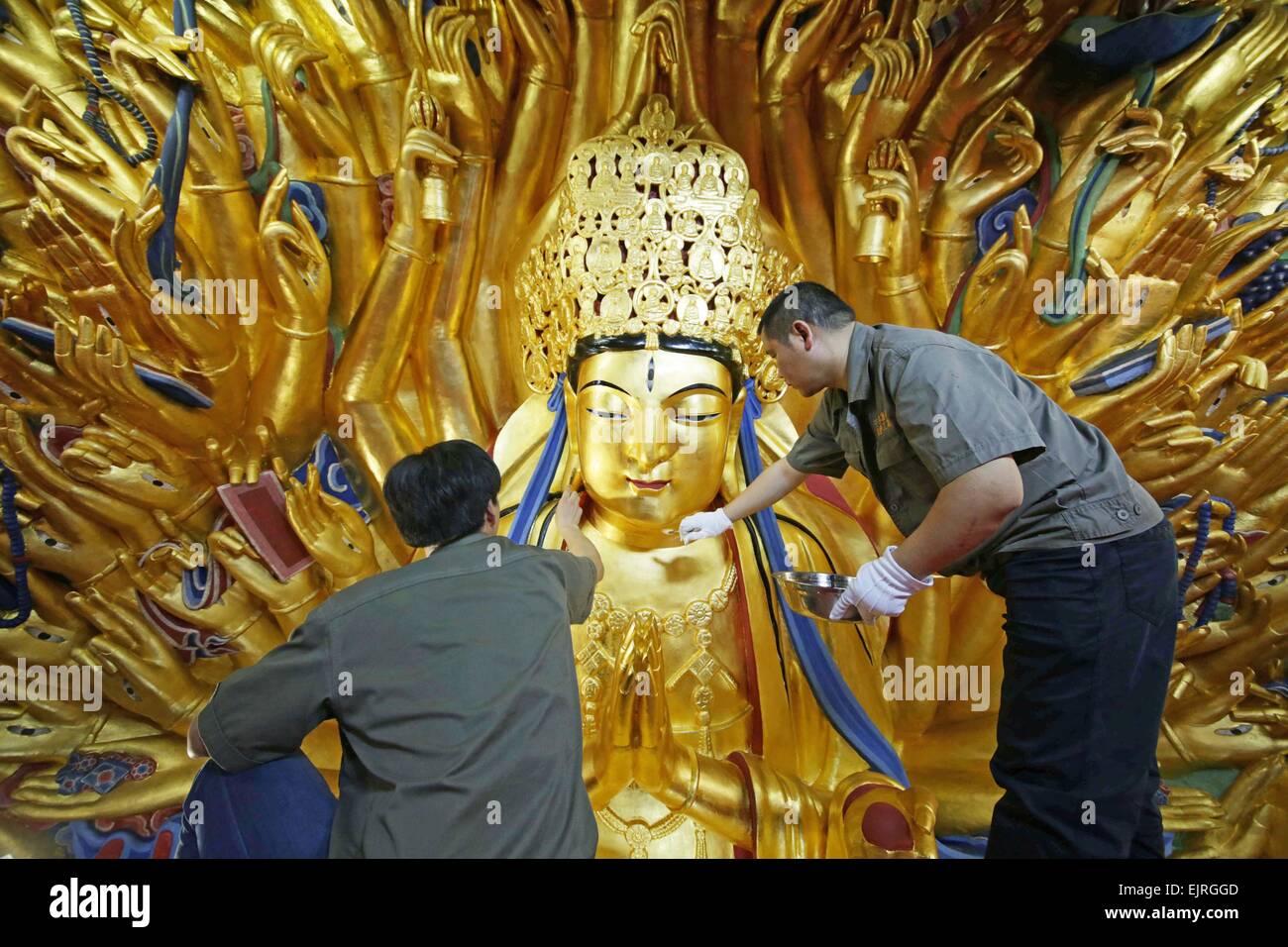 Chongqing, China. 31st Mar, 2015. Workers restore a sculpture of Qianshou Guanyin (bodhisattva with a thousand hands) on Mount Baoding in Dazu District in the municipality of Chongqing, southwest China, March 31, 2015. The sculpture with gold foil, carved in the cave with 7.7 meters high and 12.5 meters wide, could date back to Southern Song Dynasty (1127 to 1279). The restoration work has entered the final phase and is supposed to be finished in June this year, after which the sculpture will be reopened to public. © Luo Guojia/Xinhua/Alamy Live News Stock Photo