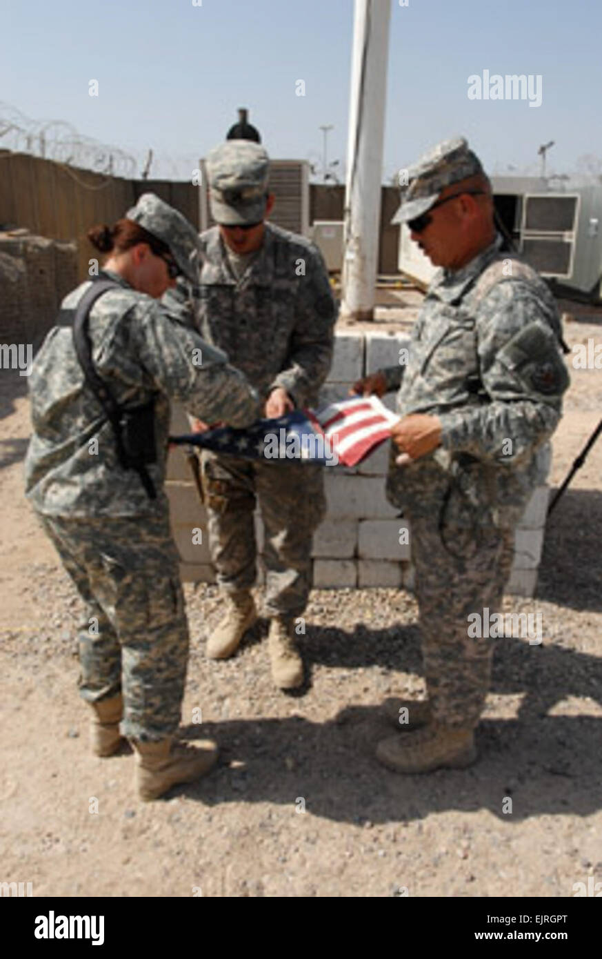 Sgt. 1st Class Sherry Ellithorpe, Patrol Base Shaibah Logistics Military Advisory Team noncommissioned officer in charge, Sgt. Joshua Garriott, PB Shaibah LMAT fuel advisor, and Staff Sgt. Alejandro  Montano, PB Shaibah LMAT, fold the U.S. flag after lowering it for the final time at PB Shaibah, March 30, 2010. The base was returned to full Iraqi control during a March 30 ceremony. Photo credit: Sgt. Benjamin Kibbey.  U.S. transfers facilities to Iraqi control as drawdown continues  /-news/2010/04/07/36947-us-transfers-facilities-to-iraqi-control-as-drawdown-continues/index.html Stock Photo