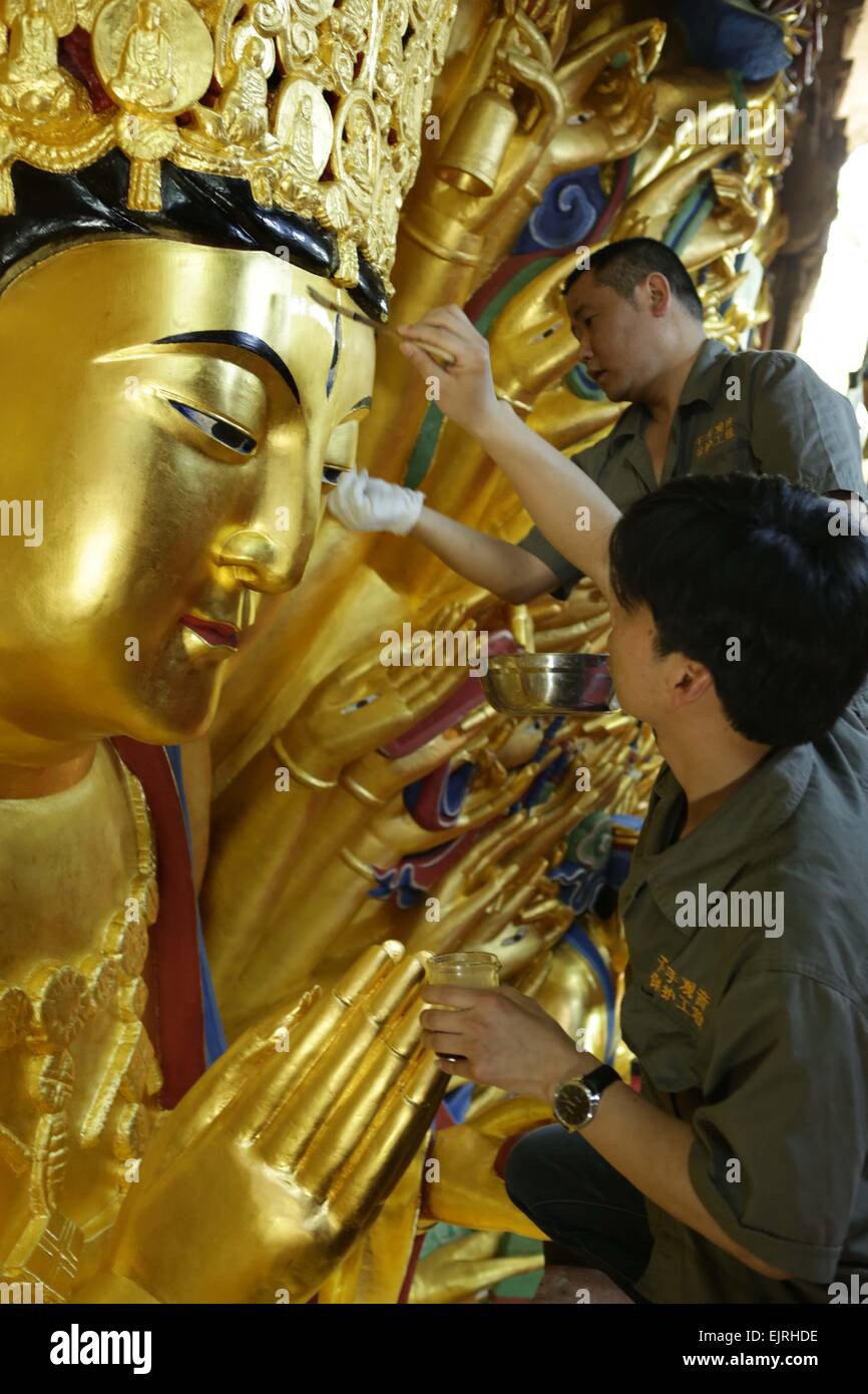 Chongqing, China. 31st Mar, 2015. Workers restore a sculpture of Qianshou Guanyin (bodhisattva with a thousand hands) on Mount Baoding in Dazu District in the municipality of Chongqing, southwest China, March 31, 2015. The sculpture with gold foil, carved in the cave with 7.7 meters high and 12.5 meters wide, could date back to Southern Song Dynasty (1127 to 1279). The restoration work has entered the final phase and is supposed to be finished in June this year, after which the sculpture will be reopened to public. © Luo Guojia/Xinhua/Alamy Live News Stock Photo