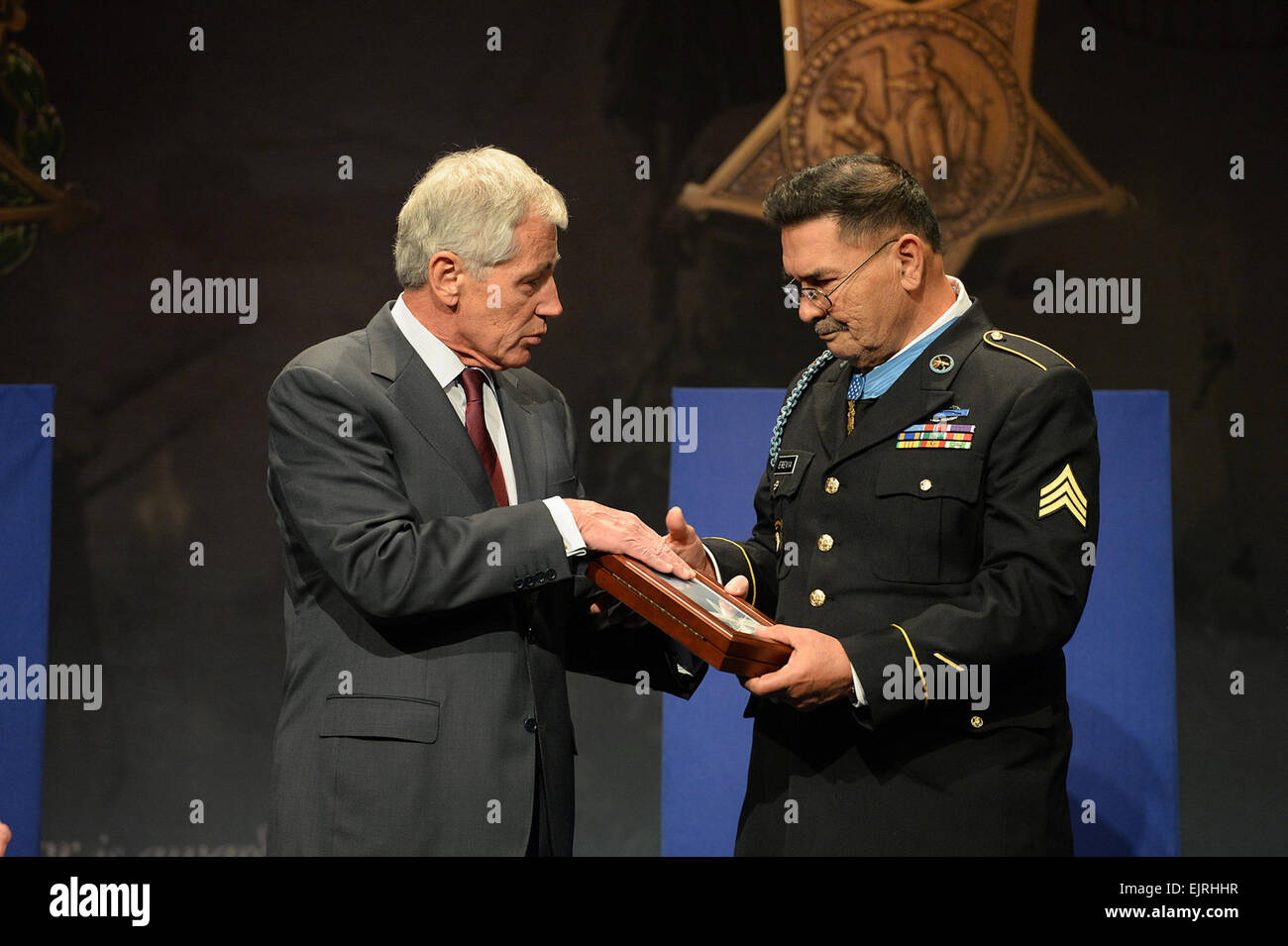 Spec. 4 Santiago J. Erevia is presented the Medal of Honor Flag by Secretary of Defense Chuck Hagel after being inducted into the Hall of Heroes during a ceremony at the Pentagon, Washington D.C., March 19, 2014. Erevia distinguished himself May 21, 1969, while serving as a radio-telephone operator during a search-and-clear mission near Tam Ky City, in the Republic of Vietnam.  Mr. Leroy Council Stock Photo
