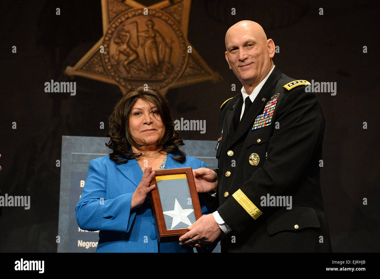 Chief of Staff of the Army, Gen. Raymond T. Odierno presents the Medal of Honor Flag to Miriam Adams, on behalf of her uncle, Pvt. Joe Gandara, one of 24 Army veterans honored during the Valor 24 Hall of Heroes Induction ceremony, held at the Pentagon, Washington D.C., March 19, 2014.  Mr. Leroy Council Stock Photo