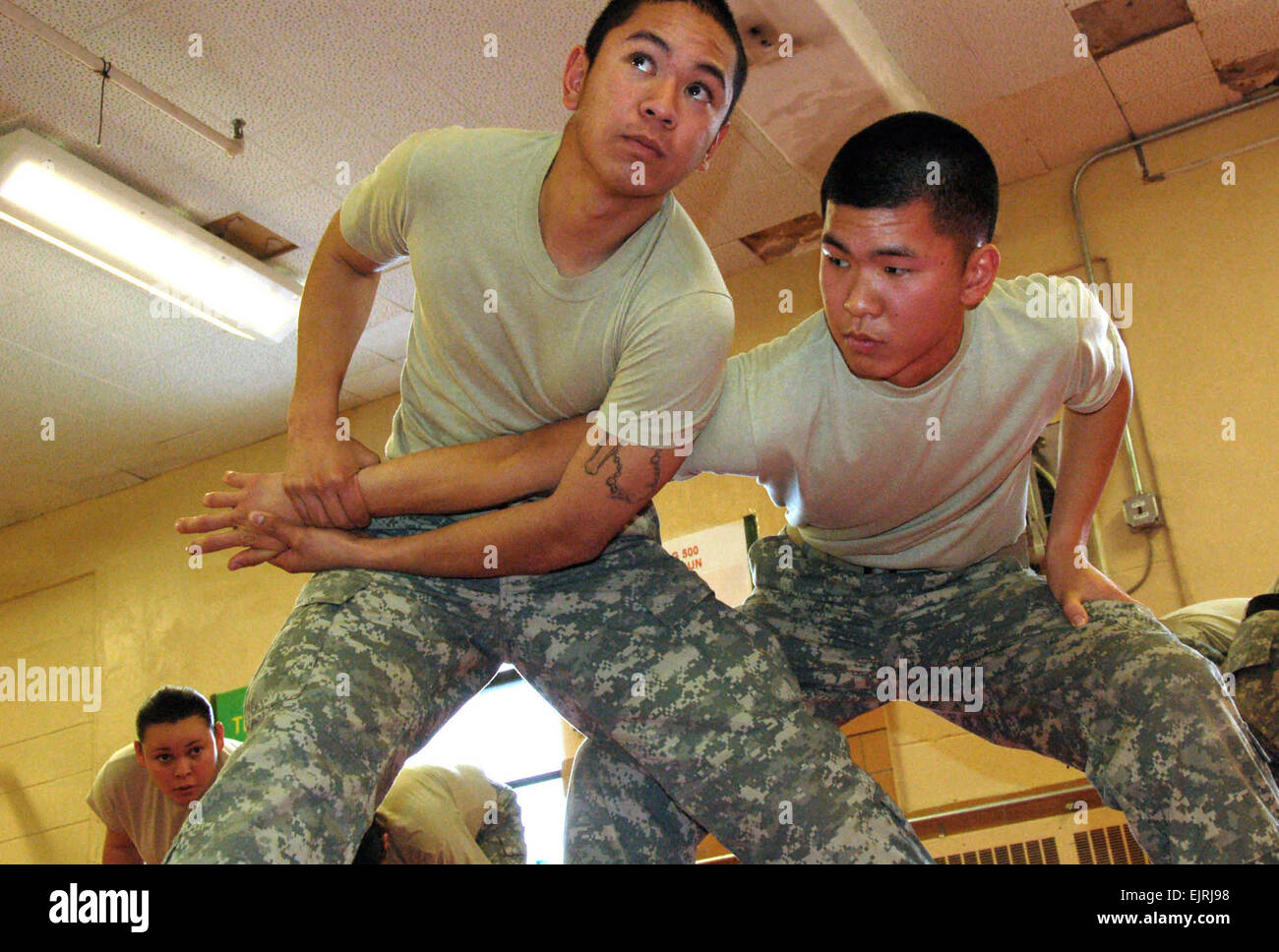 Pfc. Ji Chong left listens to an instructor while putting a submission hold on Pfc. Andrew Bituin during a nonlethal weapons training class at Muscatatuck Urban Training Center in Indiana. The training, designed to induce compliance and control rather than injury, is part of deployment training for Chong and Bituinís unit, 40th Infantry Division. The task force is scheduled to deploy to Kosovo later this year, where they will be conducting law and order and security missions at Camp Bondsteel. Stock Photo