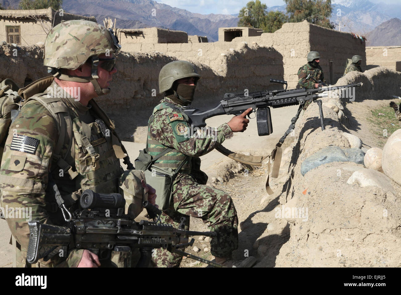 U.S. Army Spc. Mason Lembke of West Union, Iowa, an infantryman with Headquarters and Headquarters Company, 1st Battalion, 133rd Infantry Regiment, Task Force Ironman, a part of the 2nd Brigade Combat Team, 34th Infantry Division, Task Force Red Bulls, and Afghan National Army soldiers provide security during a dismounted patrol through Mangow village Jan. 21. TF Ironman pulled security while members of 319th Tactical Psychological Operations Company, Task Force Stingray, talked to villagers about security within their village. U.S. Army  Spc. Kristina L. Gupton, Task Force Red Bulls Public Af Stock Photo