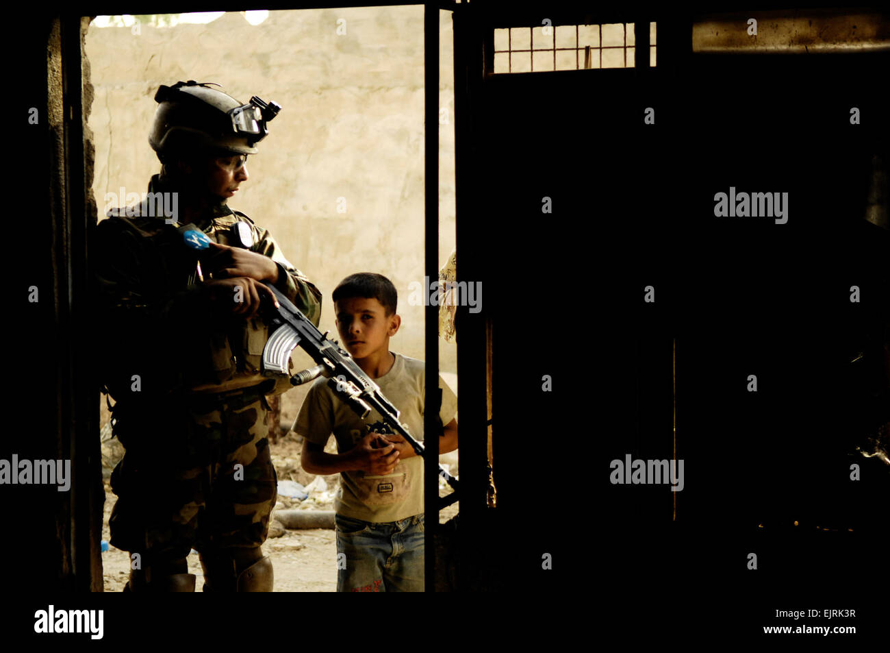 An Iraqi Army Soldier looks down at a boy as he watches U.S. Soldiers and Iraqi soldiers search a building during a joint patrol in Shulla, Iraq, June 19, 2008. The U.S. Soldiers are assigned to 3rd Platoon, Bravo Company, 2nd Brigade, 502nd Infantry Regiment.  Staff Sgt. Manuel J. Martinez Stock Photo