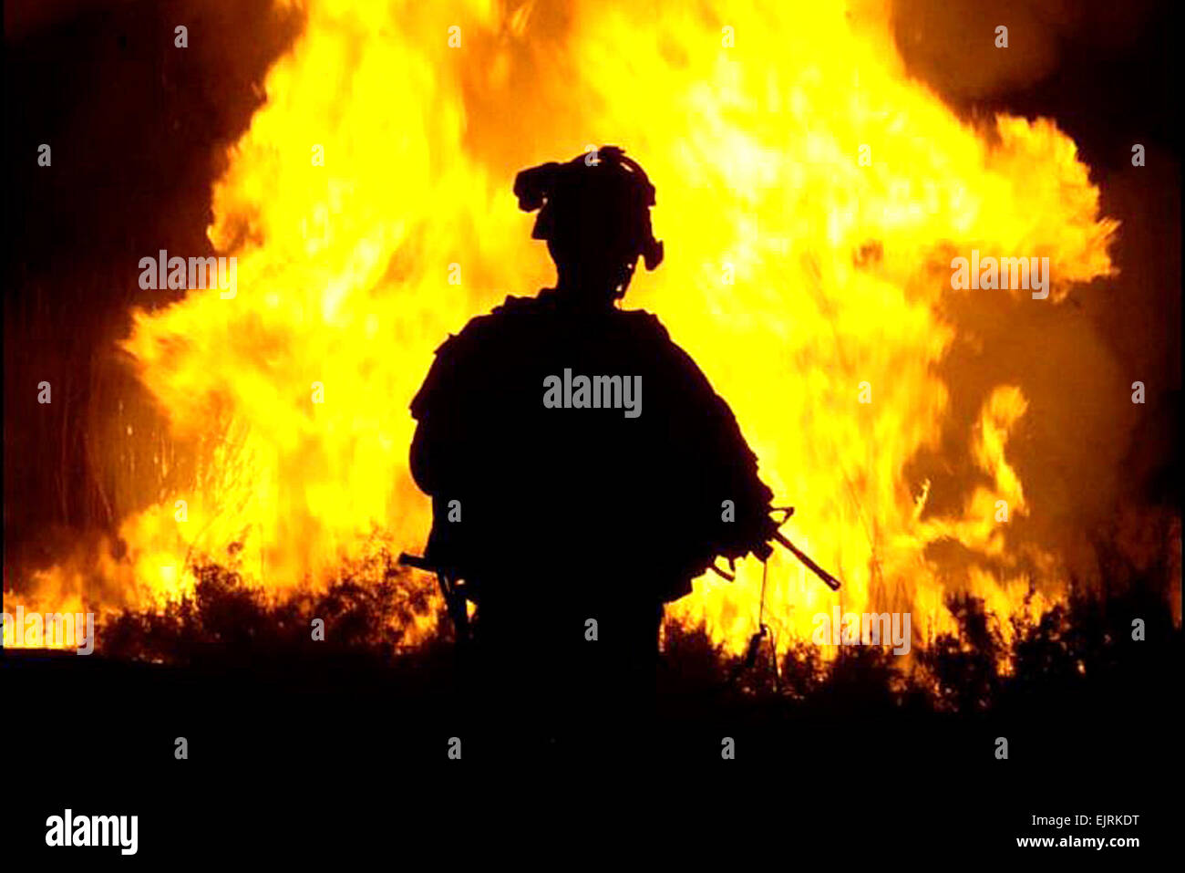 U.S. Army Sgt. William Reese watches flames rise into the night sky after setting canal vegetation ablaze in Tahwilla, Iraq, July 30, 2008. Extremists have been using the canal's thick vegetation to plant bombs under the cover of darkness. The soldiers are assigned to Company B, 1st Battalion, 6th Infantry Regiment. Spc. David J. Marshall Stock Photo