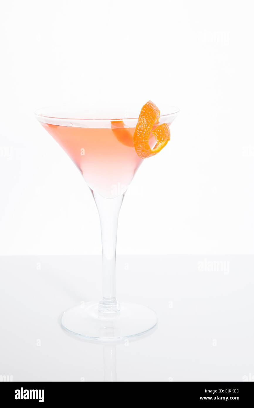 A martini glass is filled with a pink cosmopolitan cocktail with a piece of orange garnish on the rim Stock Photo
