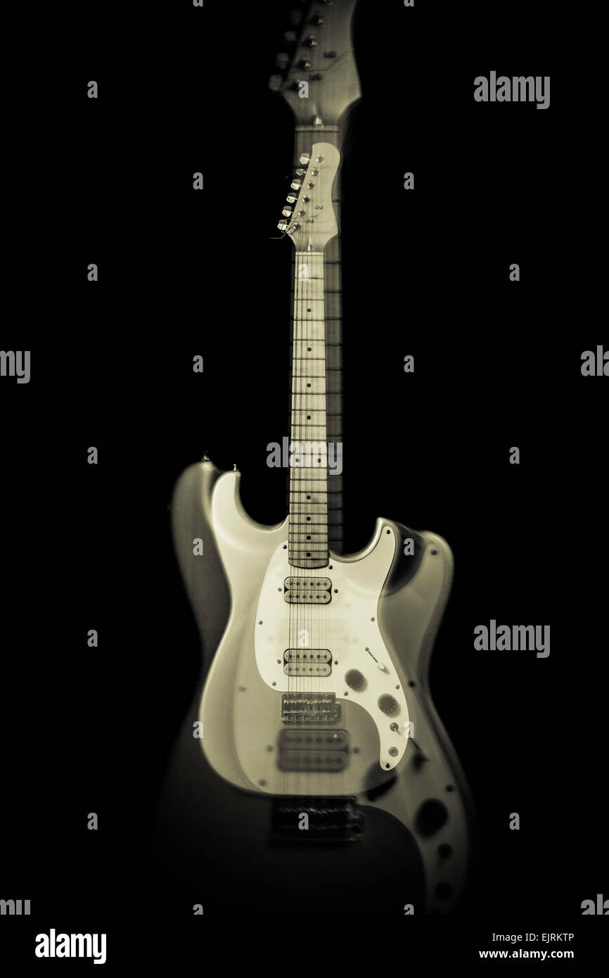 An monochrome electric guitar with a ghost image; photographic technique: racking the lens; pure black background Stock Photo