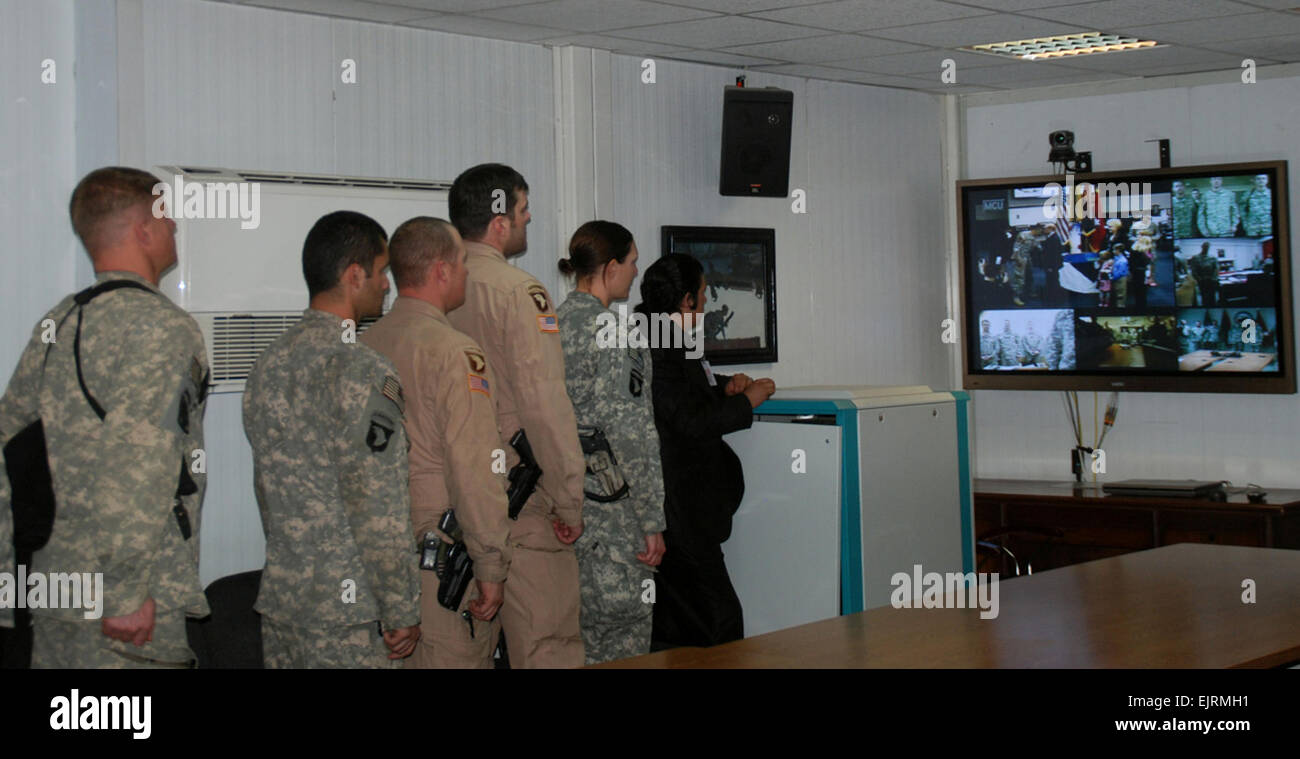 Soldiers at CJTF-101 Headquarters at Bagram look at the video teleconferencing screen as former Staff Sgt. Gary Harris is presented with the Bronze Star and Silver Star, at Fort Campbell, Ky.  Spc. George Welcome, 101st CAB PAO Stock Photo