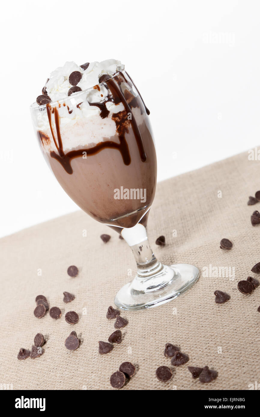 A glass is filled with a chocolate cocktail, topped with whipped cream, chocolate syrup, and chocolate chips Stock Photo