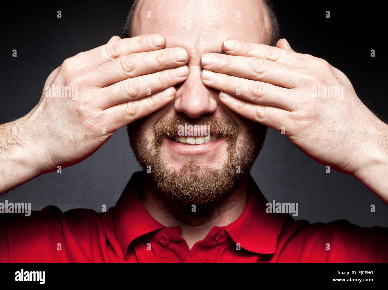 smiling man hide his eyes with hands Stock Photo