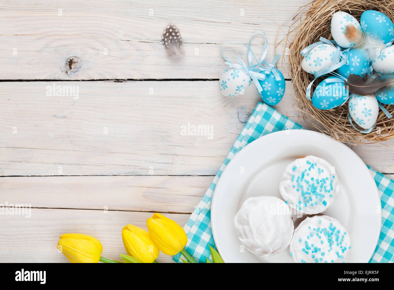 Easter background with blue and white eggs in nest, yellow tulips and ...