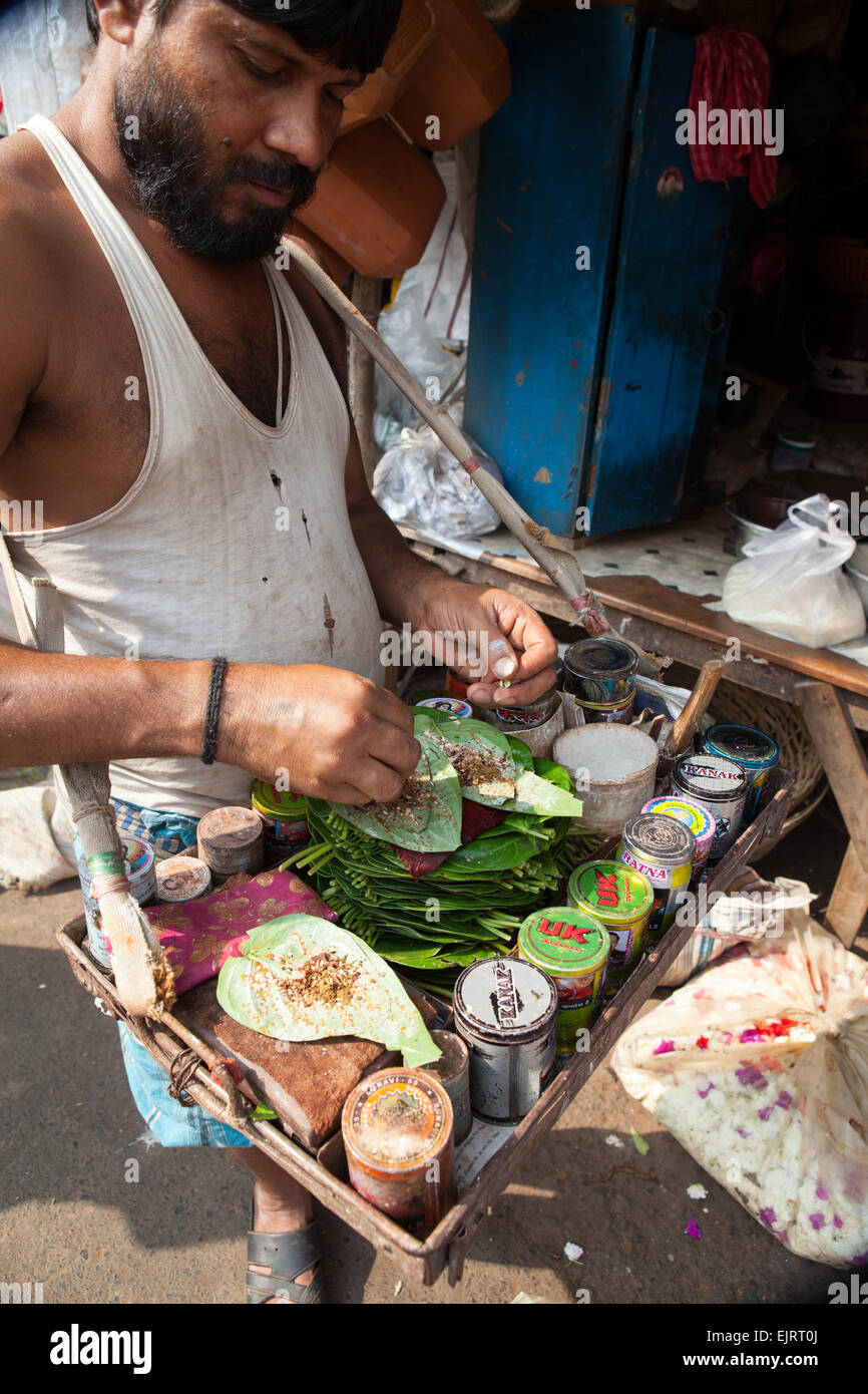 A paan vendor prepares a mixture of tobacco and areca nut on a betel