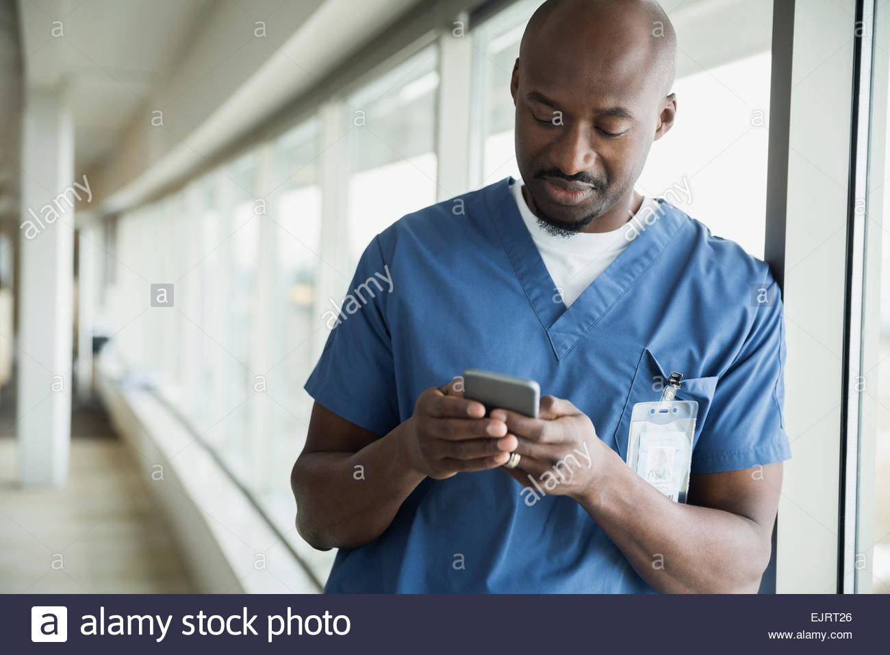 Surgeon text messaging at window Stock Photo