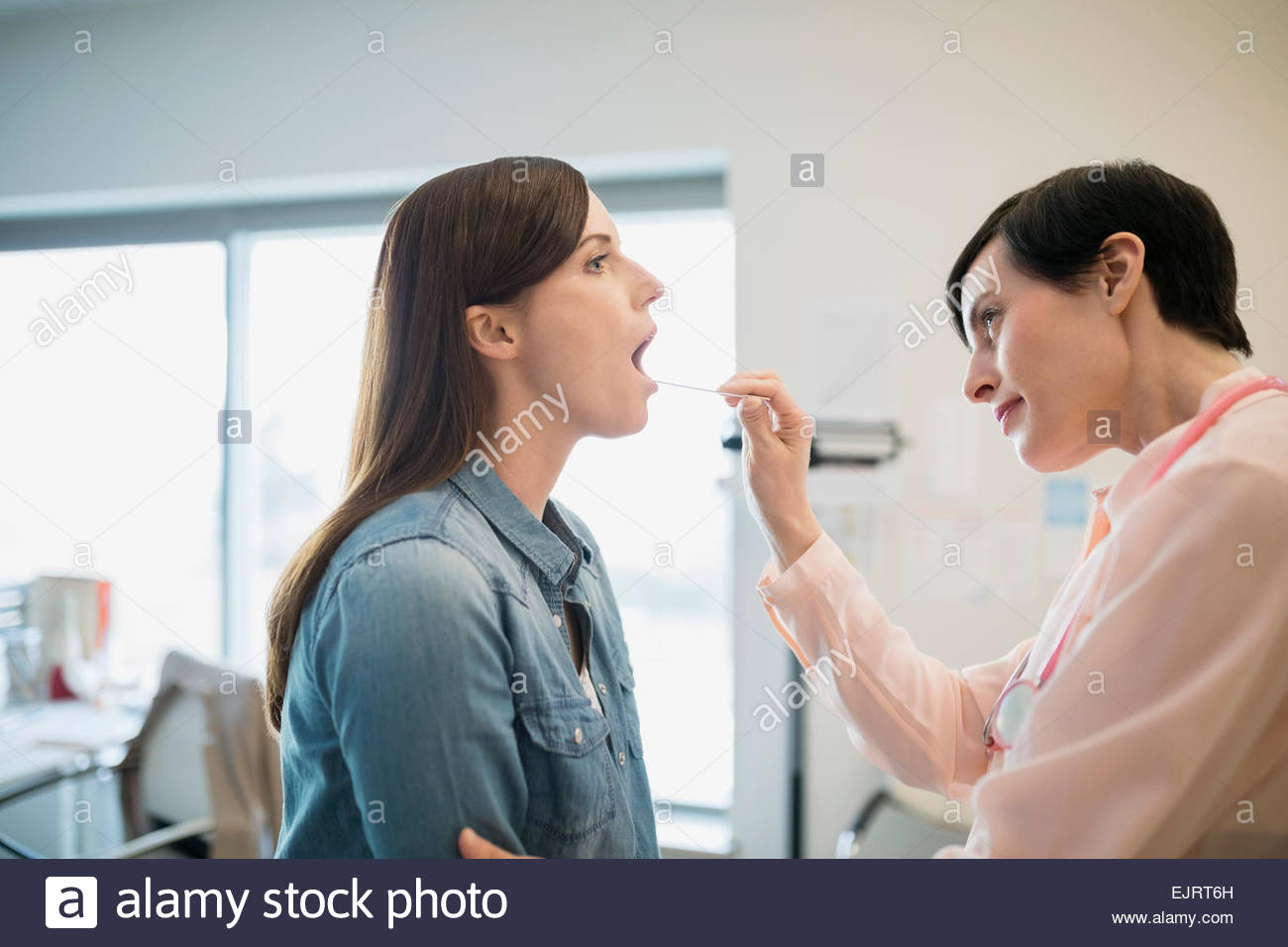 Doctor checking patients tongue with tongue depressor Stock Photo Alamy