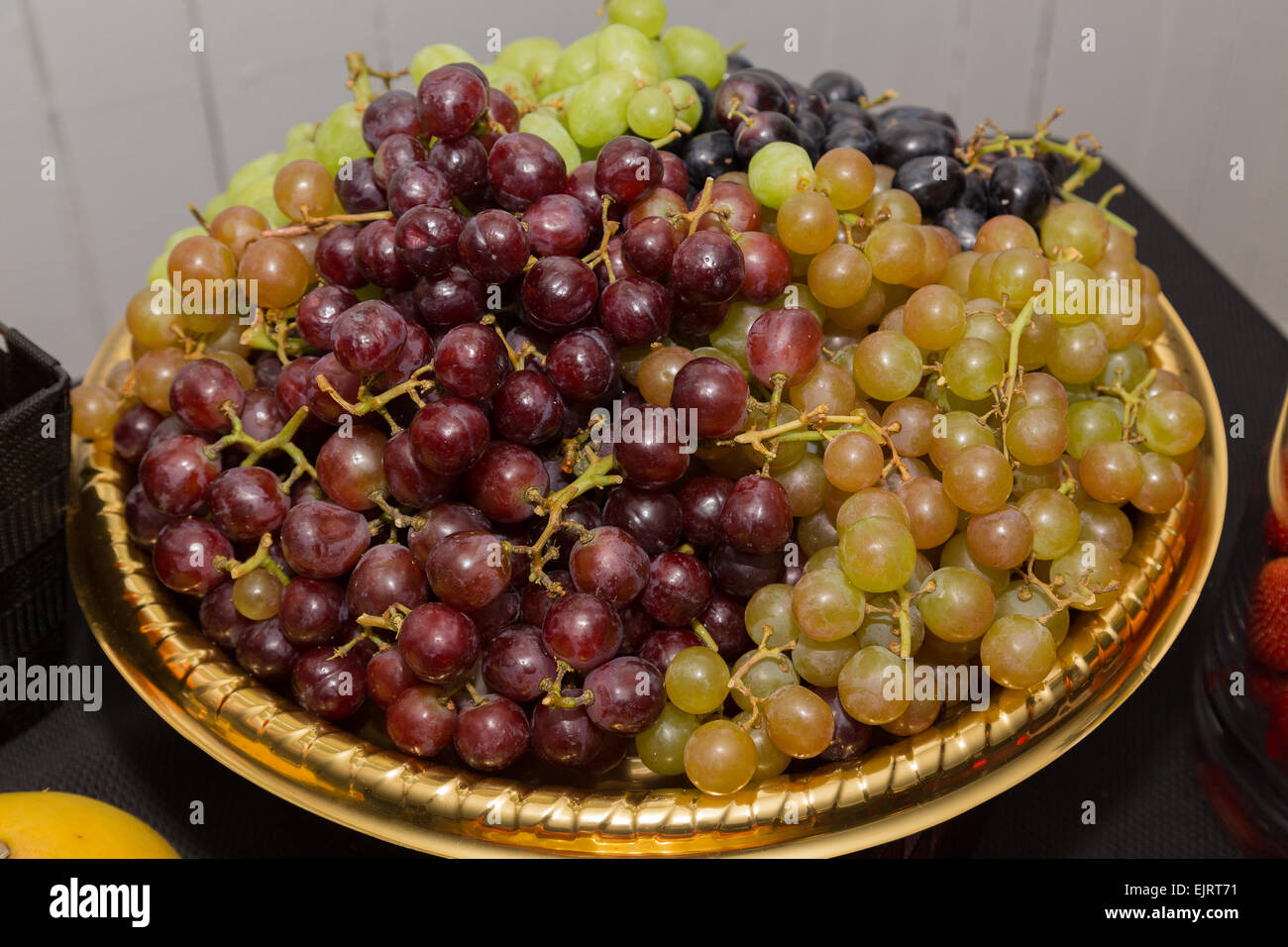 Closeup to lots of red, green and black grapes in a bowl on a table Stock Photo