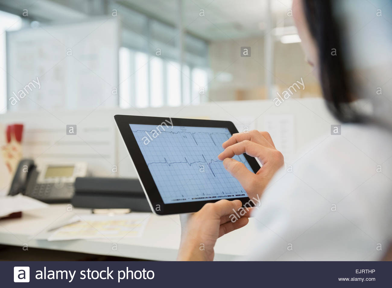 Doctor examining electrocardiogram on digital tablet Stock Photo