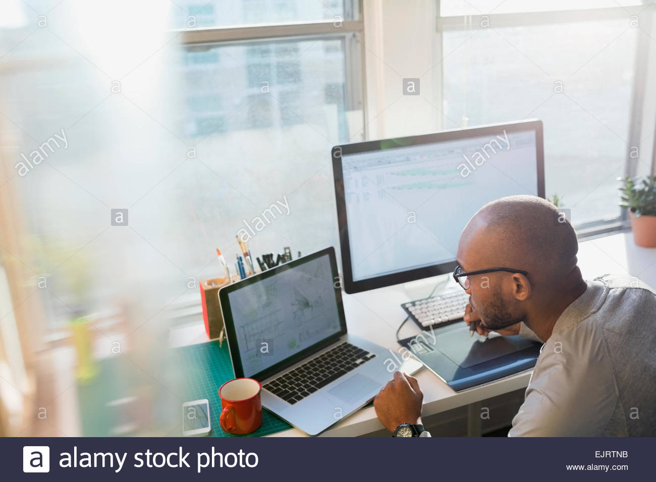 Designer using laptop at office desk Stock Photo - Alamy