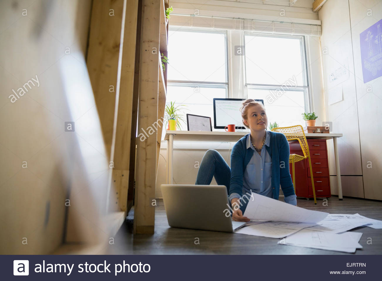 Architect reviewing blueprints on office floor Stock Photo