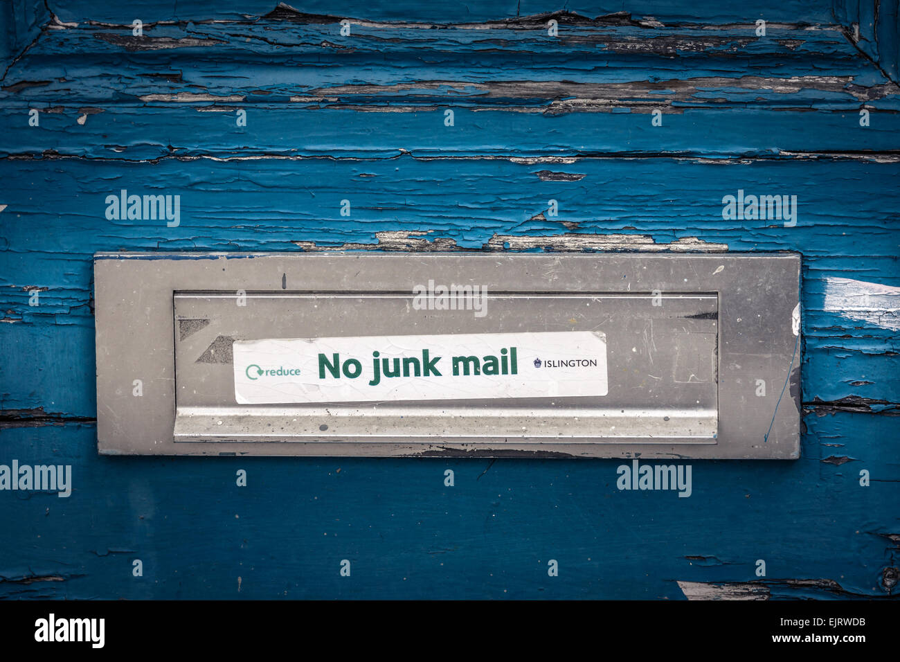 A Letterbox on a weathered door in North London with a 'No Junk Mail' sticker. Stock Photo