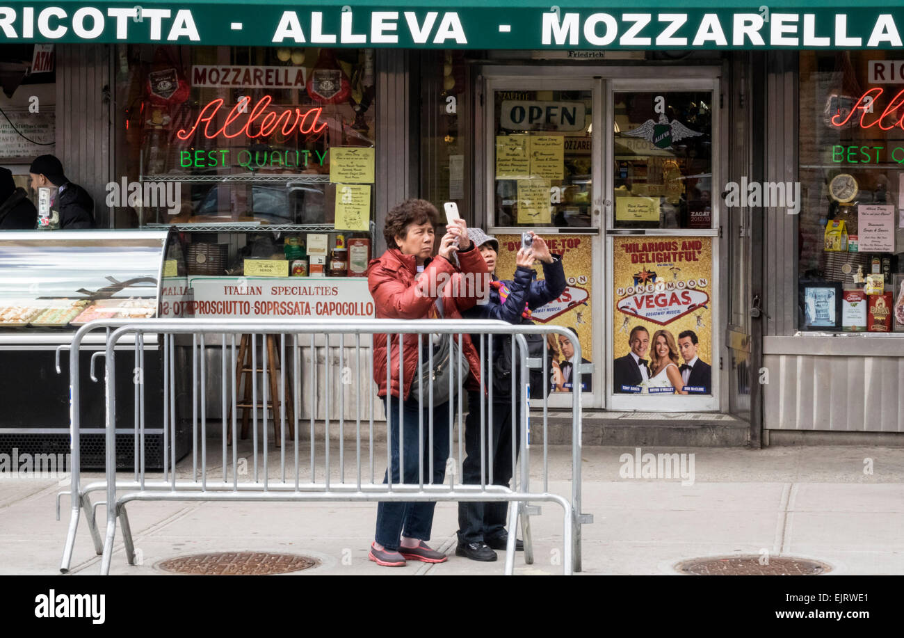 Two elderly Asian women using cell phones cameras in Little Italy in New York City Stock Photo