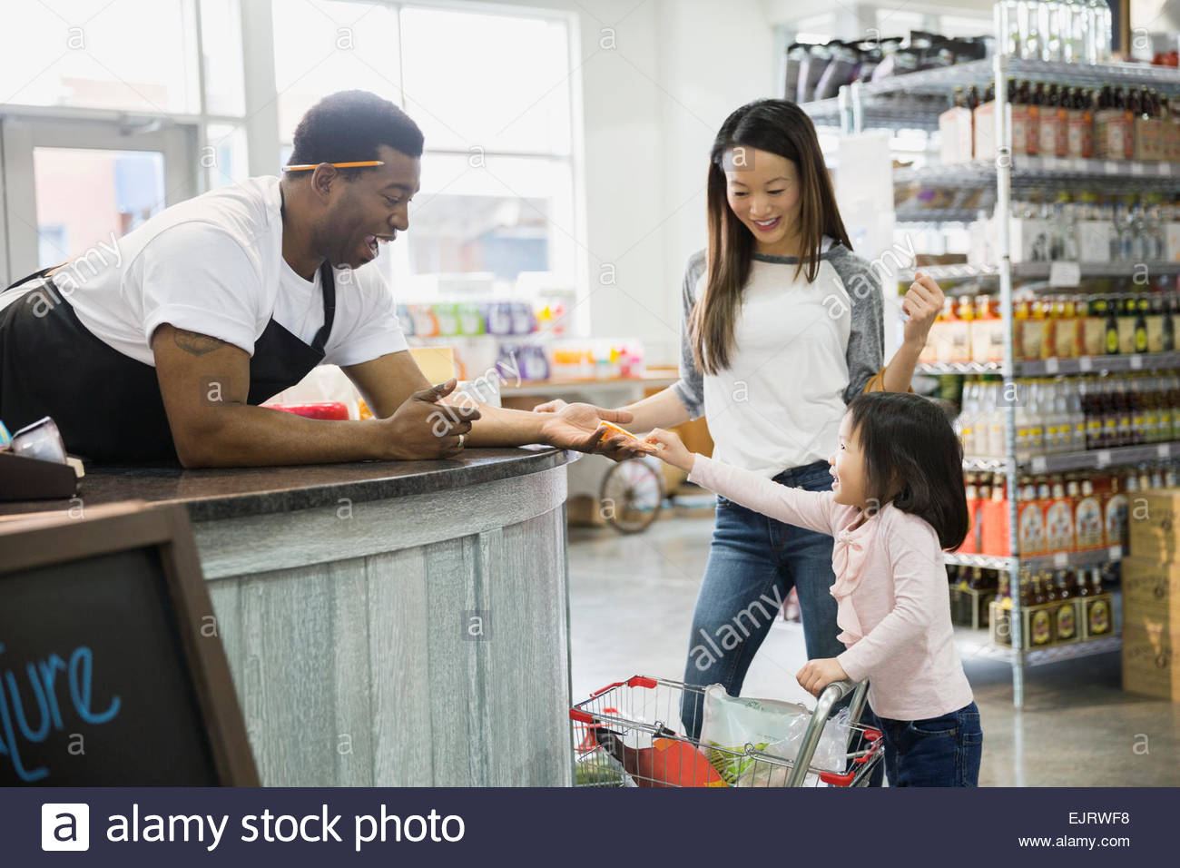 Deli worker giving mother and daughter cheese sample Stock Photo Alamy
