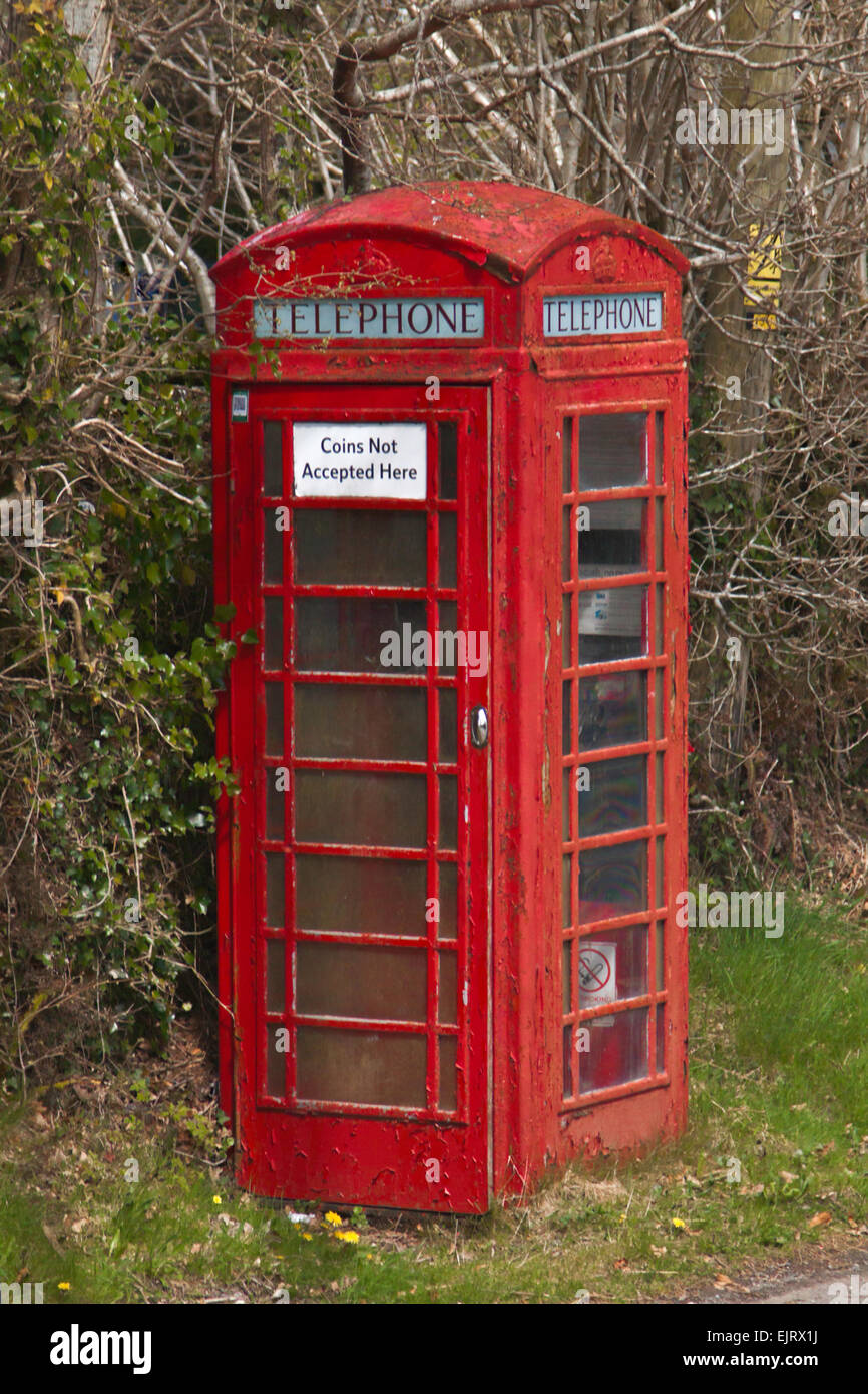 Weathered iconic red telephone box along a country road, in rural setting, county Devon, England, Great Britain, United Kingdom. Stock Photo