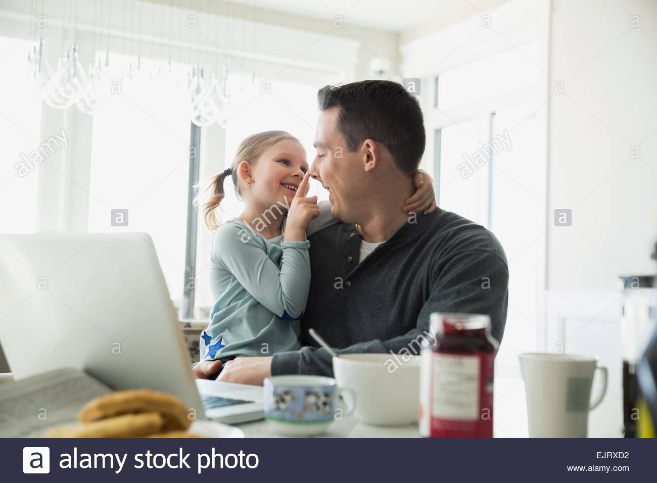 Affectionate daughter touching fathers nose in kitchen Stock Photo