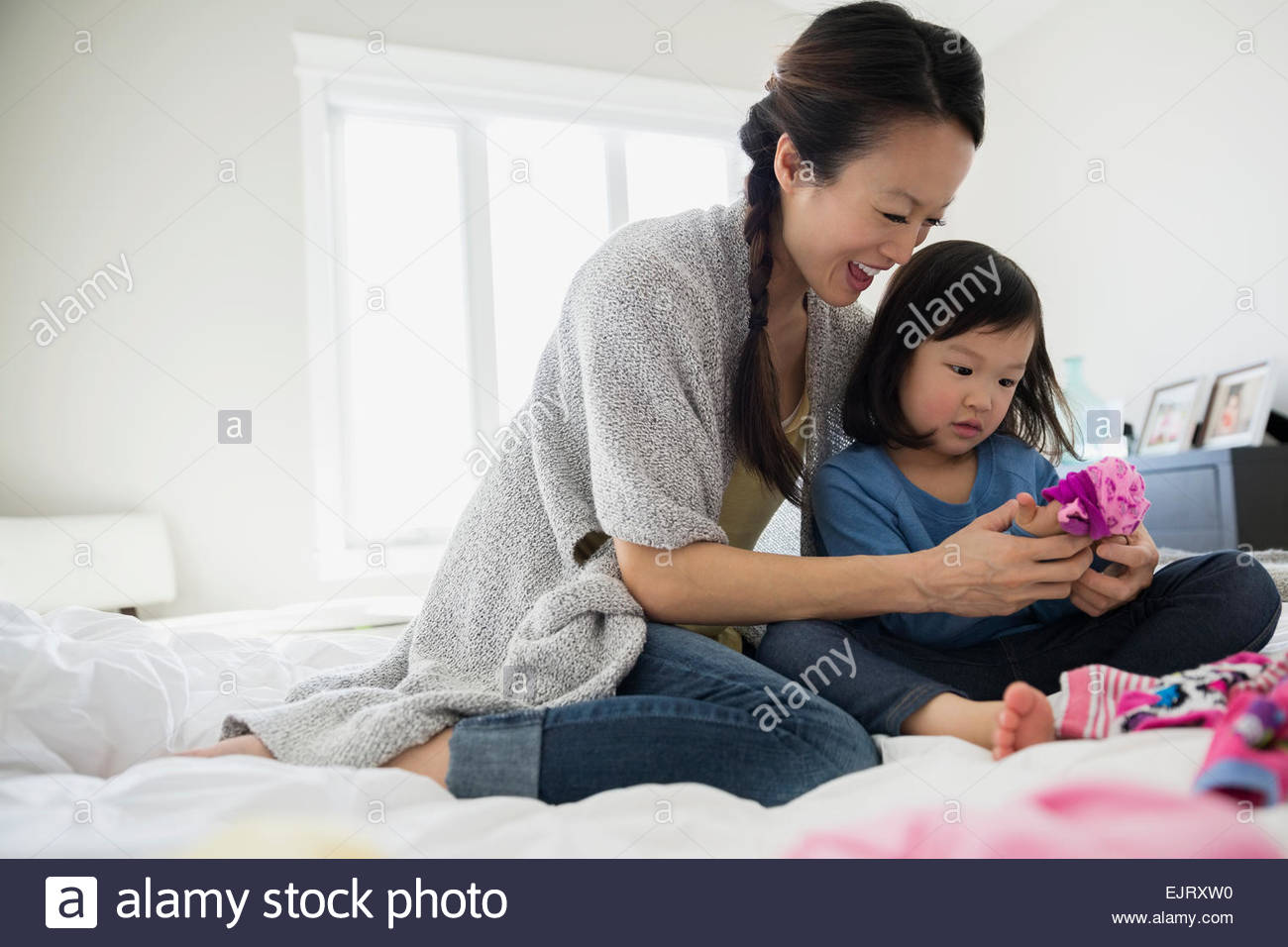 Mother and daughter sorting laundry on bed Stock Photo