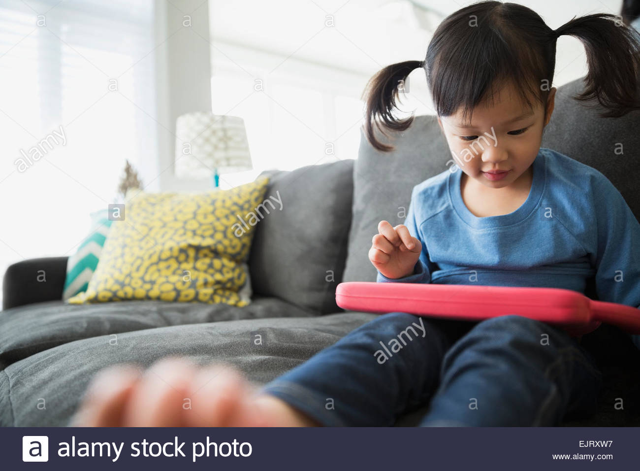 Girl with pigtails using digital tablet on sofa Stock Photo