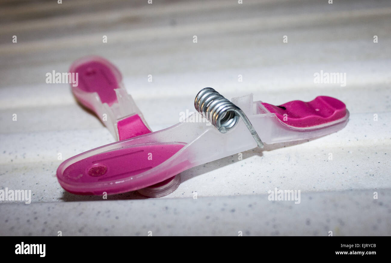 Plastic, pink broken peg on a white kitchen draining board. Stock Photo