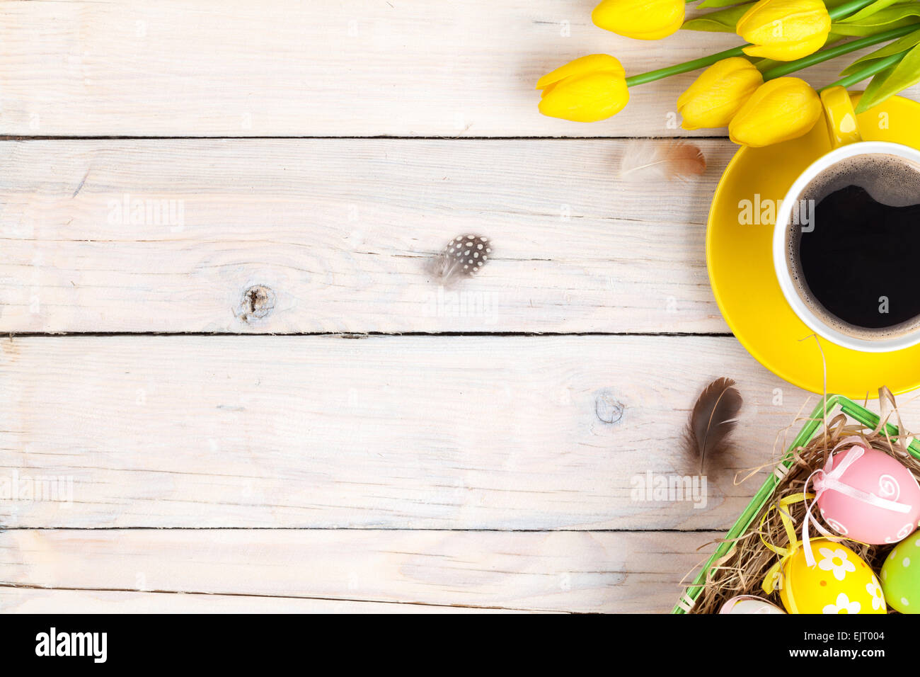 Easter background with colorful eggs and yellow tulips over white wood ...