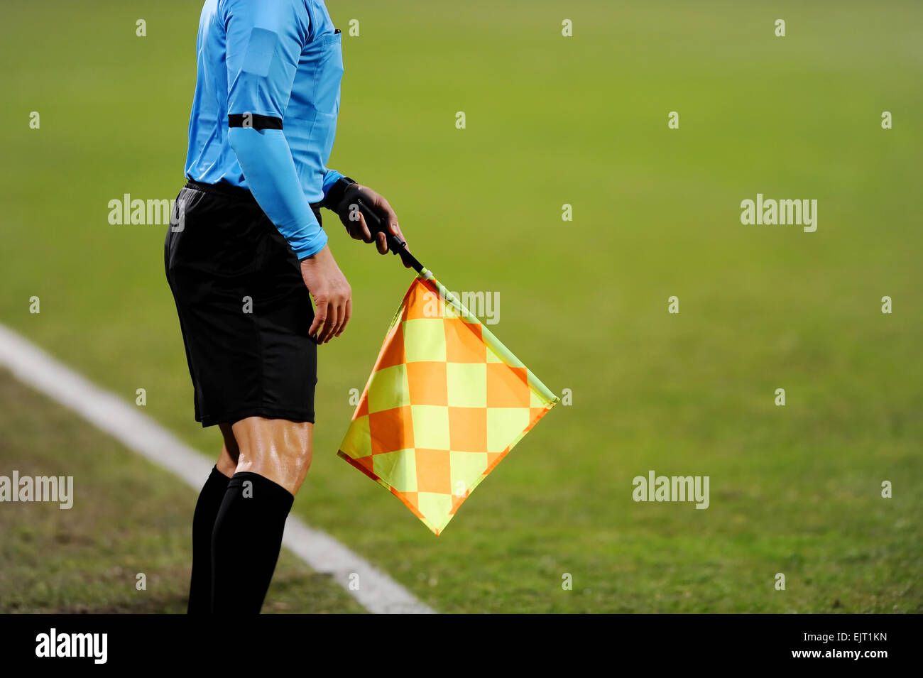 Assistant referees signalling with the flag on the sideline during a