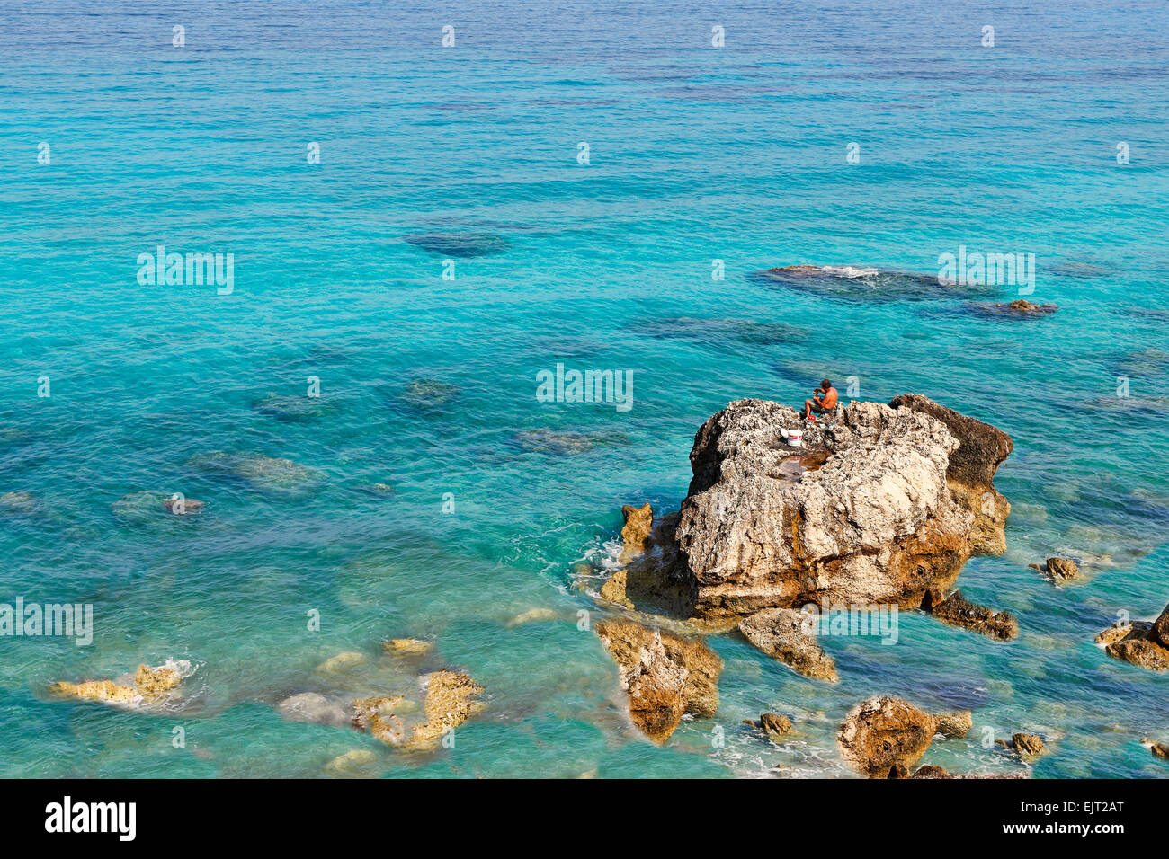 A Fisherman on the rocks of Pefkoulia in Lefkada, Greece Stock Photo
