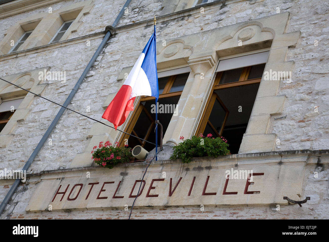 Close-up of the front facade of the Town Hall in Tournon-d'Agenais, France, with the tricolore flying from the wall mounted flag Stock Photo