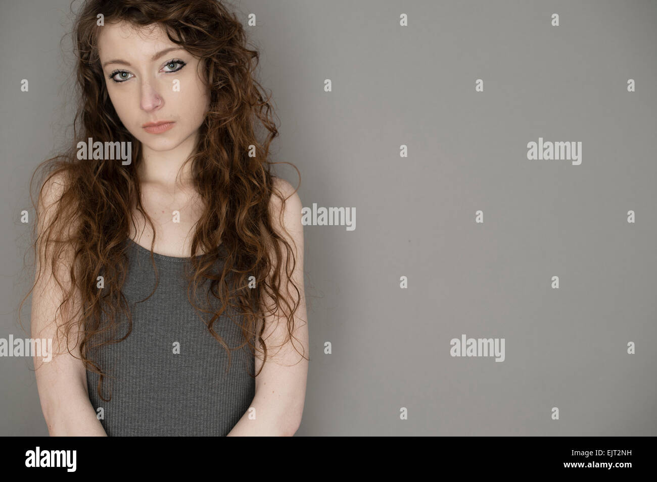 A waif-like 19 year old slim slender teenage girl young woman with long  brown hair by herself single solo standing against a grey background Stock  Photo - Alamy