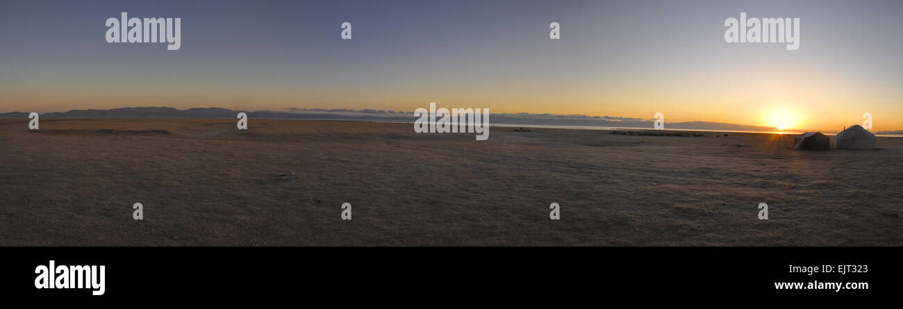 Scenic panorama of sunset on green grasslands in Kyrgyzstan with traditional nomadic yurt Stock Photo