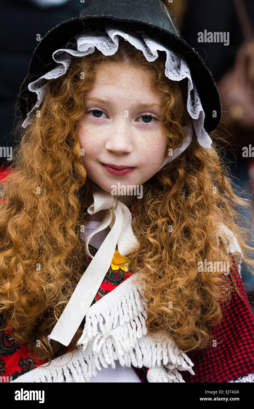 A young girl child with long red ginger hair wearing traditional welsh