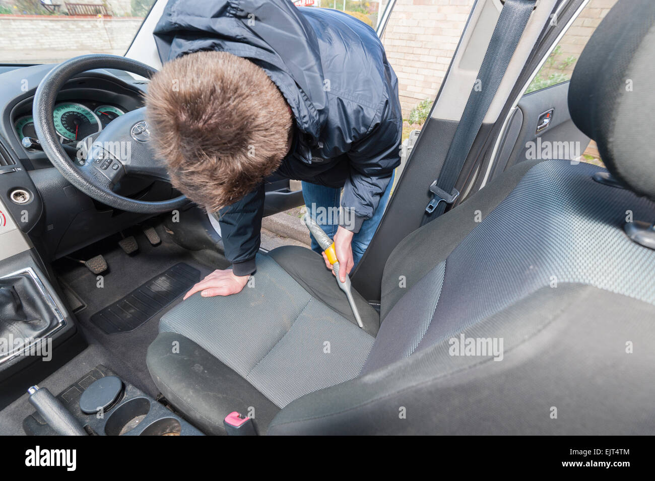 A 15 year old teenage boy cleaning the interior of a car to earn money Stock Photo