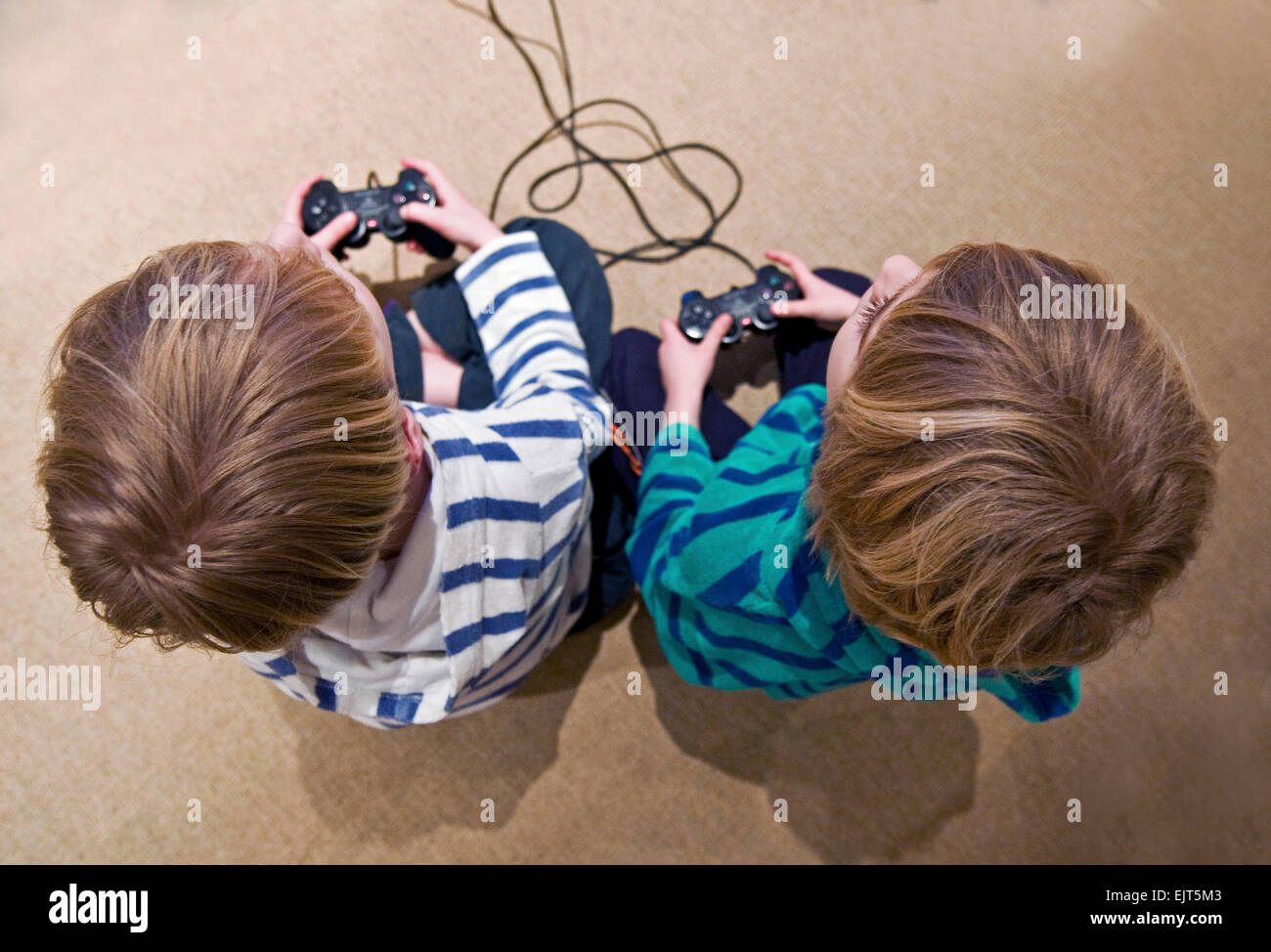 Two boys play with their Playstation console remotes Stock Photo