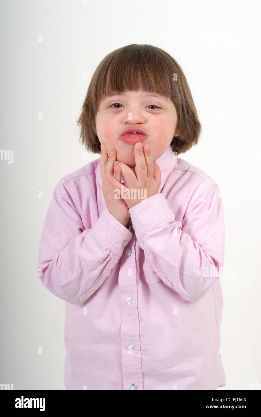 Boy with down syndrome blowing kisses. Isolated on white background. Stock Photo