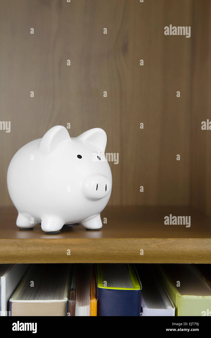 White Piggy Bank sitting on a book shelve Stock Photo - Alamy