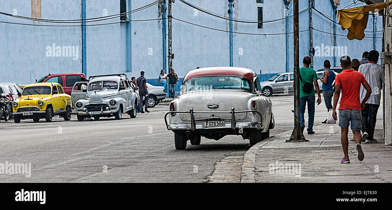 Old American cars on the streets of Havana in Cuba with pedestrians on the pavement - a typical Havana street scene. Stock Photo